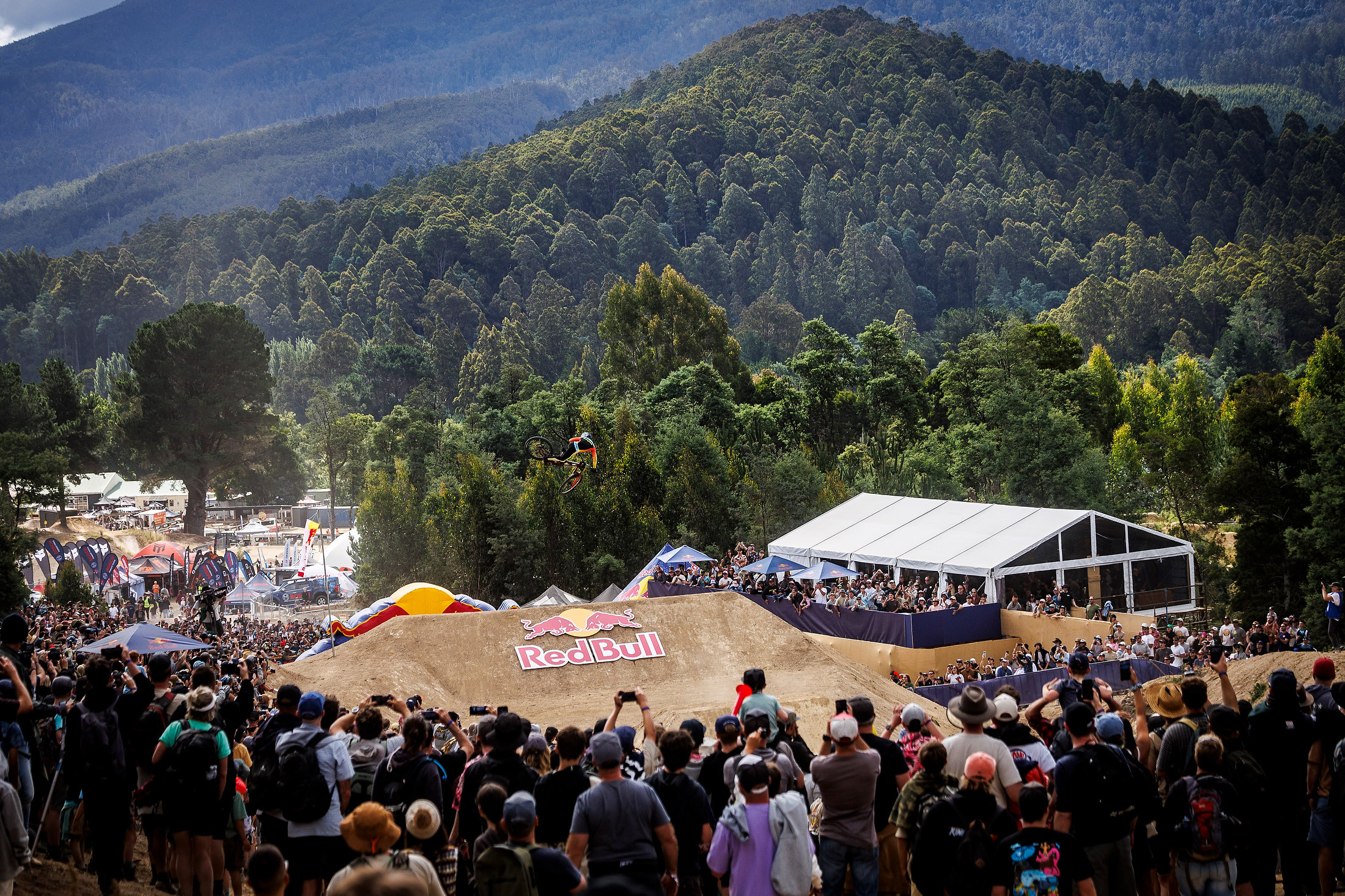 A mountain biker hits the final jump at Red Bull Hardline with the crowd in the background at Maydena Bike Park. 